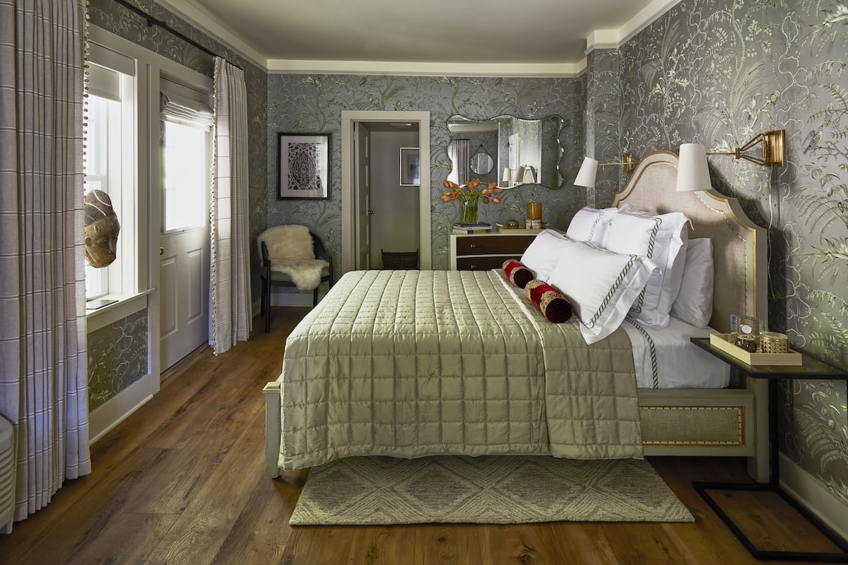 Un dormitorio con una cama grande, una mesita de noche, un aparador, un espejo y una silla.