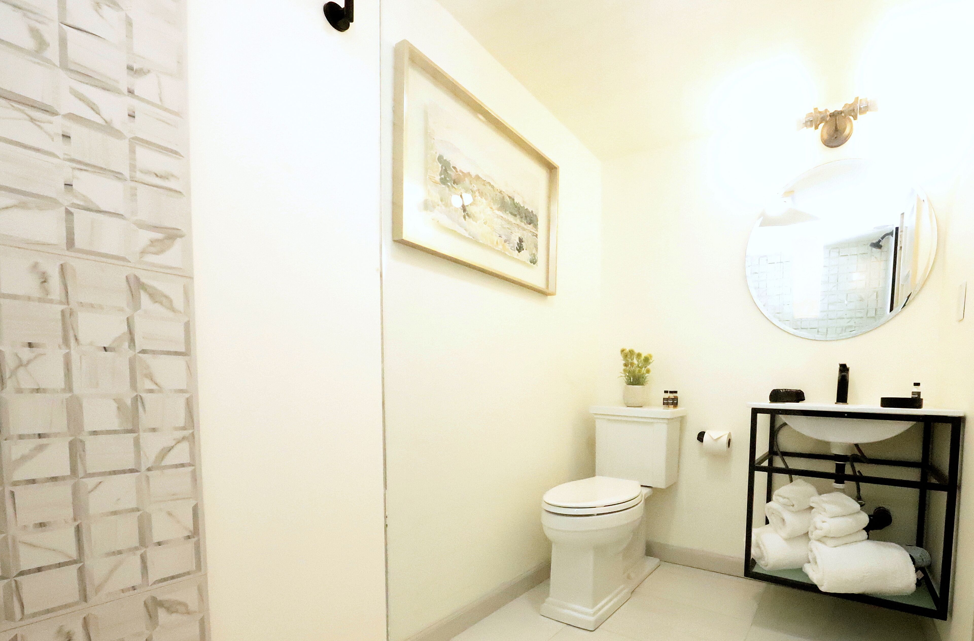 A bathroom with a toilet, sink, and a framed picture on the wall.
