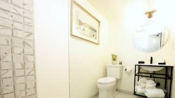 A bathroom with a toilet, sink, and a framed picture on the wall.