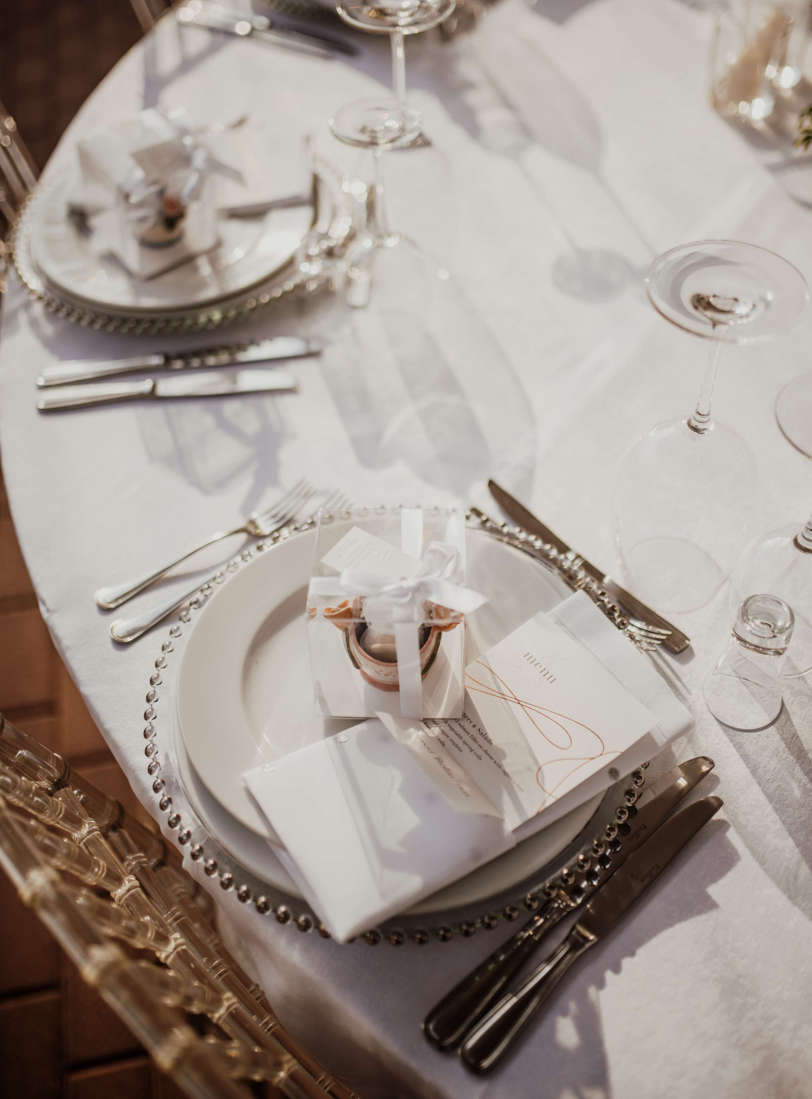 A table set for a formal meal with a white tablecloth, silverware, and clear glassware.