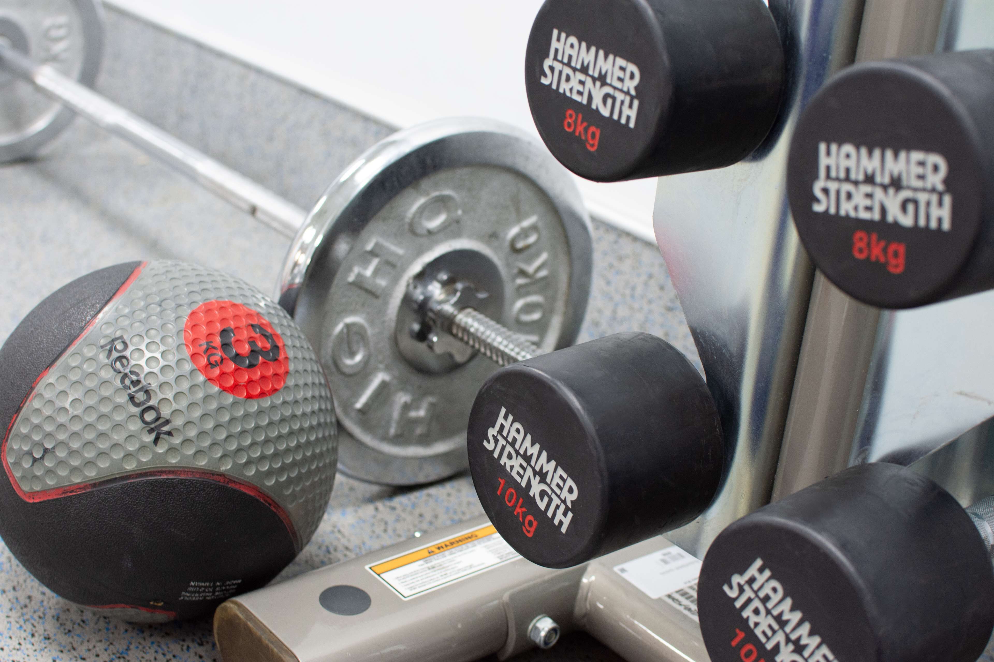 Unos pesas y una pelota Reebok sobre el suelo de un gimnasio.
