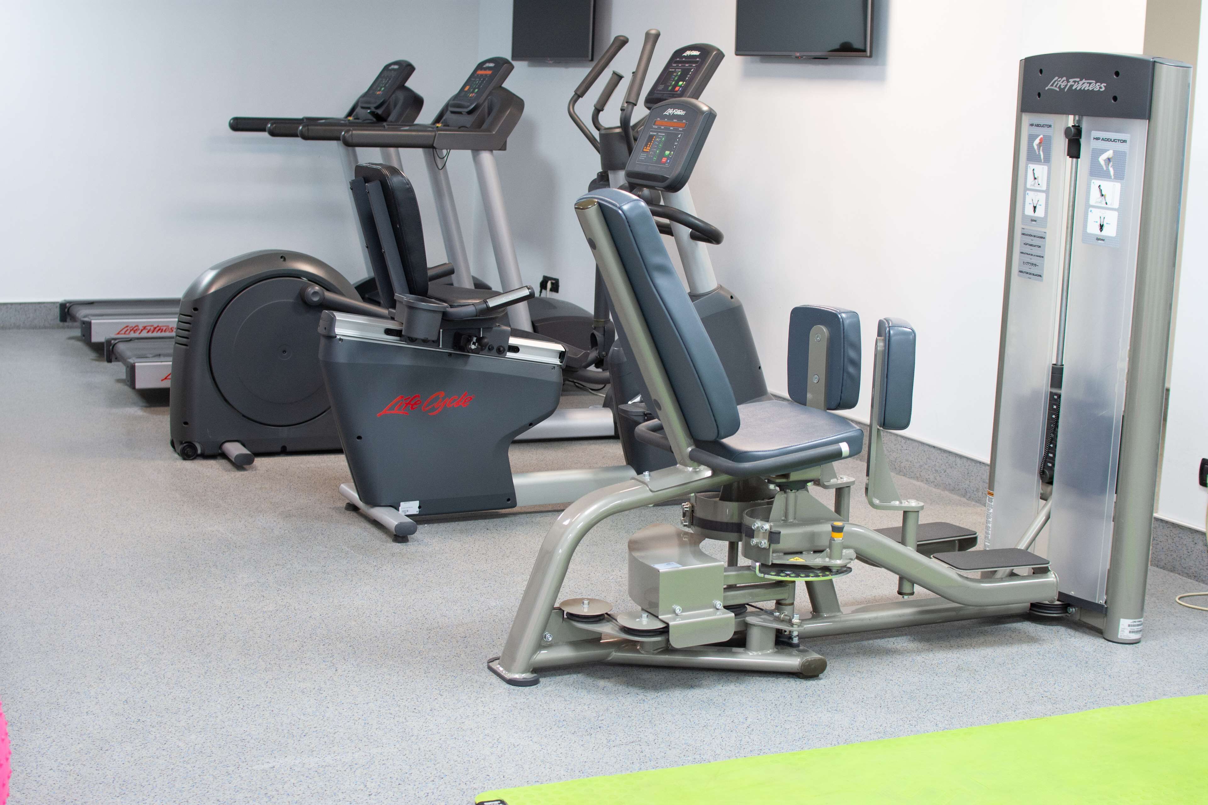 A gym with cardio machines, weight machines, and a step platform.