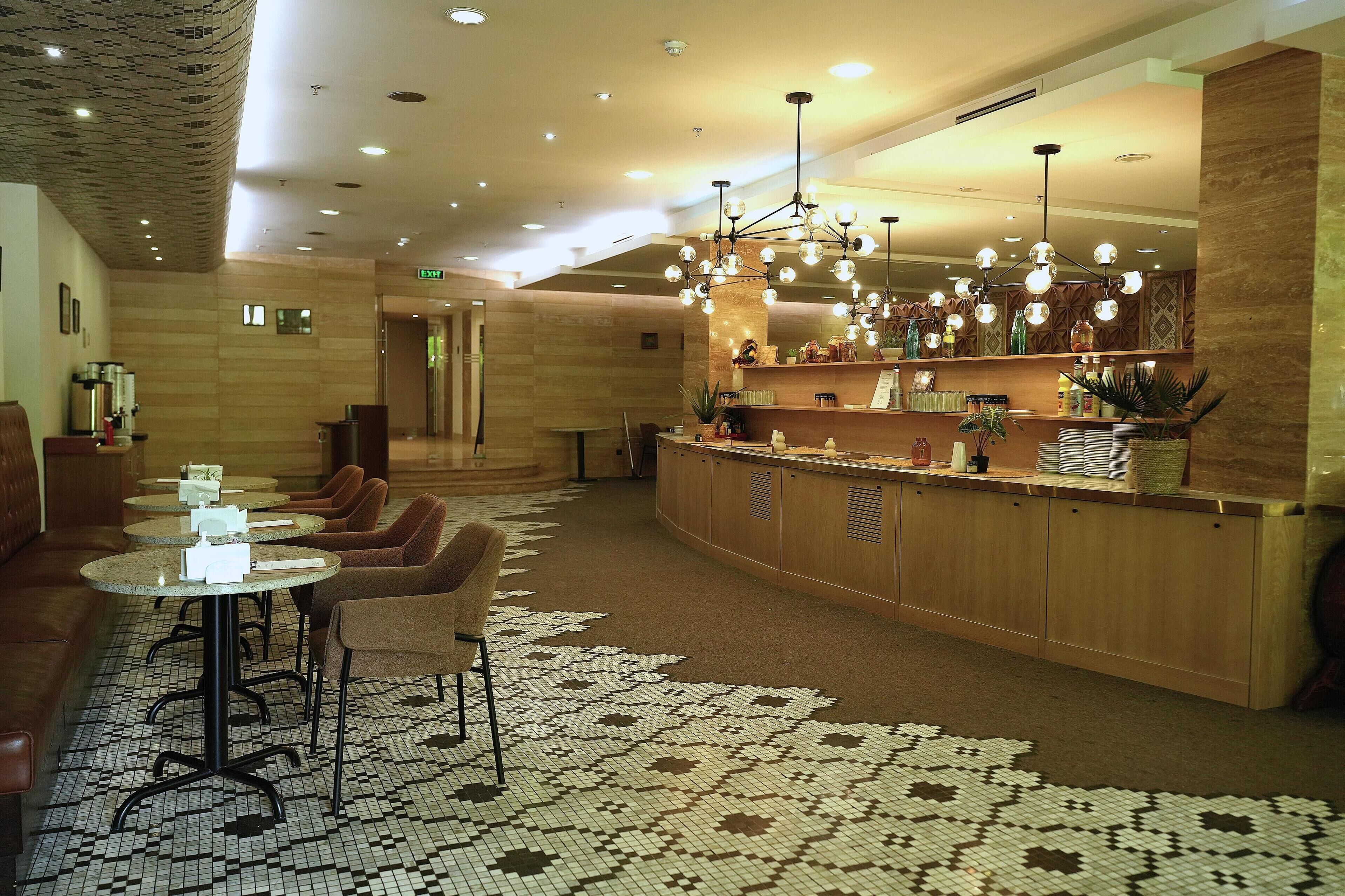 A hotel lobby with a reception desk, seating area, and a patterned carpet.