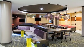 A modern hotel lobby with a curved seating area, a flat-screen TV, and a patterned carpet. - SpringHill Suites by Marriott Indianapolis Fishers (Fishers)