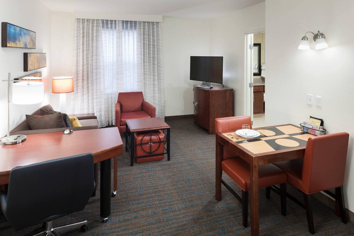 Ein Hotelzimmer mit Essbereich, Fernseher, Sofa, Lampe und kleinem Tisch.