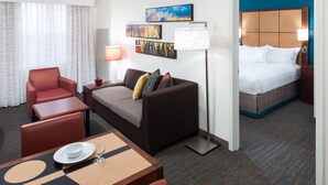 Ein Hotelzimmer mit Bett, einer Sitzecke, einem Esstisch und einem Fernseher.