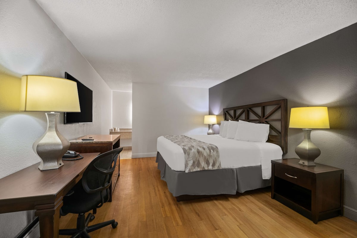 Une chambre d’hôtel équipée d’un lit, d’un bureau, d’une chaise et de deux lampes de chevet.