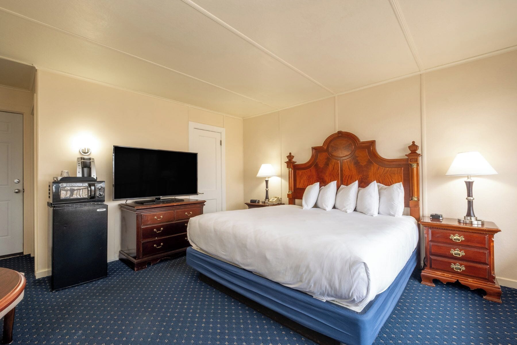 Une chambre d’hôtel avec un grand lit, une télévision, un bureau avec une lampe et une commode.