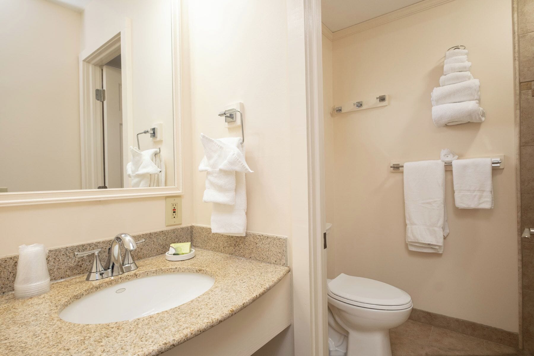 A bathroom with a sink, mirror, towel rack, and toilet.