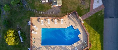 An aerial view of a swimming pool with lounge chairs and a covered patio area.