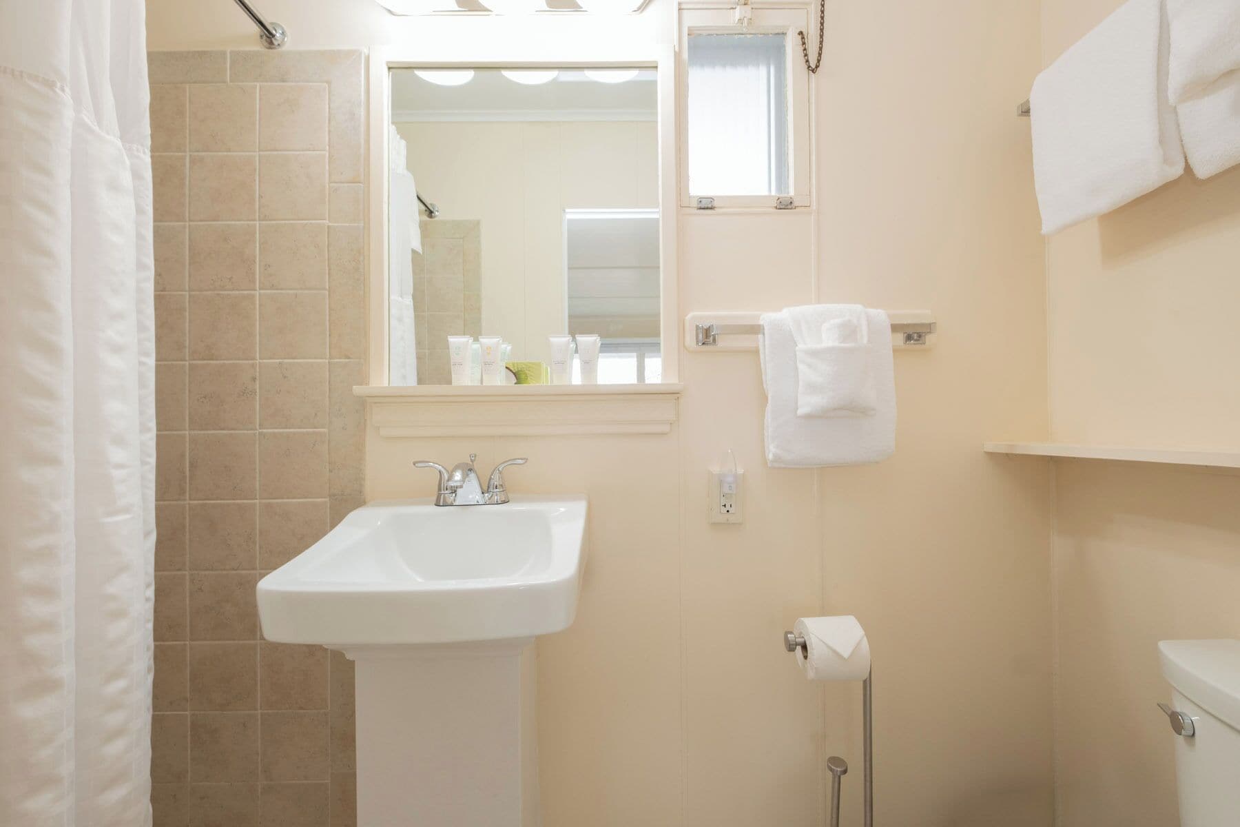 A bathroom with a sink, mirror, towel rack, and toilet.