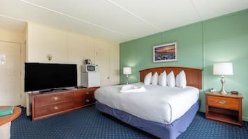 A hotel room with a bed, a TV, a microwave, a desk, and a nightstand.