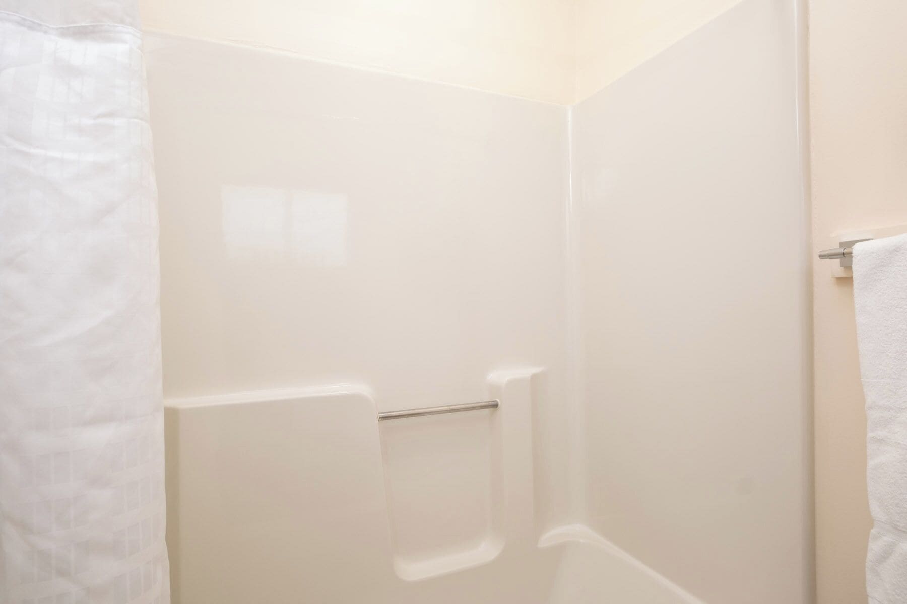 A white shower enclosure with a glass door and a towel rack.