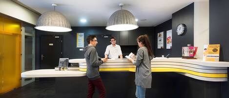 A reception desk with a modern design, featuring two pendant lights and a clock on the wall.