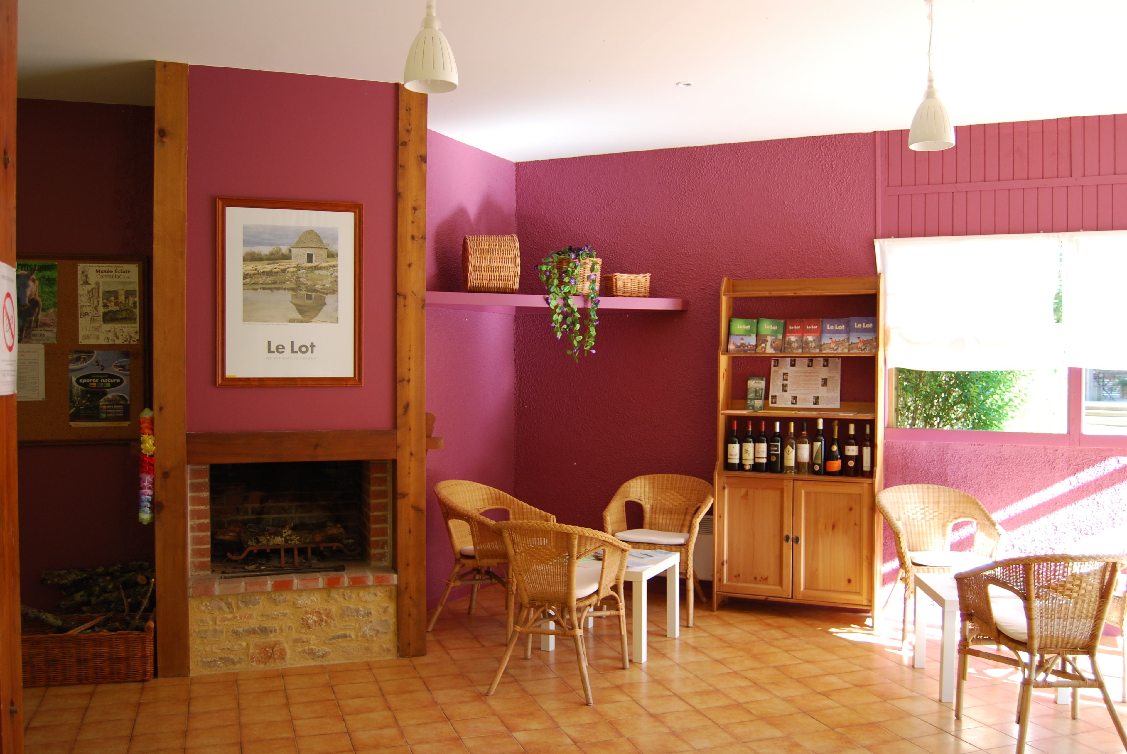 A cozy room with a fireplace, wicker chairs, a wooden cabinet with wine bottles, and a shelf with wicker baskets.