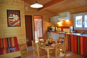 A wooden cabin interior with a dining area, kitchen, and a shower room.