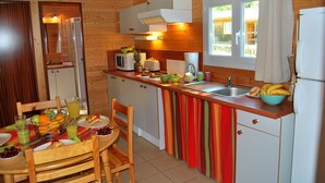 Cocina de cabaña de madera con una mesa de comedor, sillas y un armario a rayas de colores.