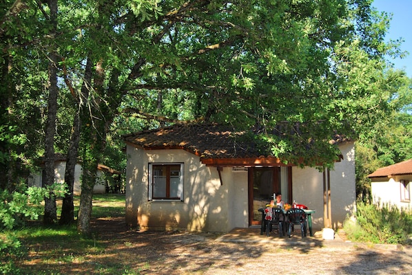 A rustic building with a tiled roof and a small patio area with a table and chairs.