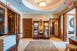 A hotel lobby with a round ceiling, wooden doors, a central clock, and a reception desk.