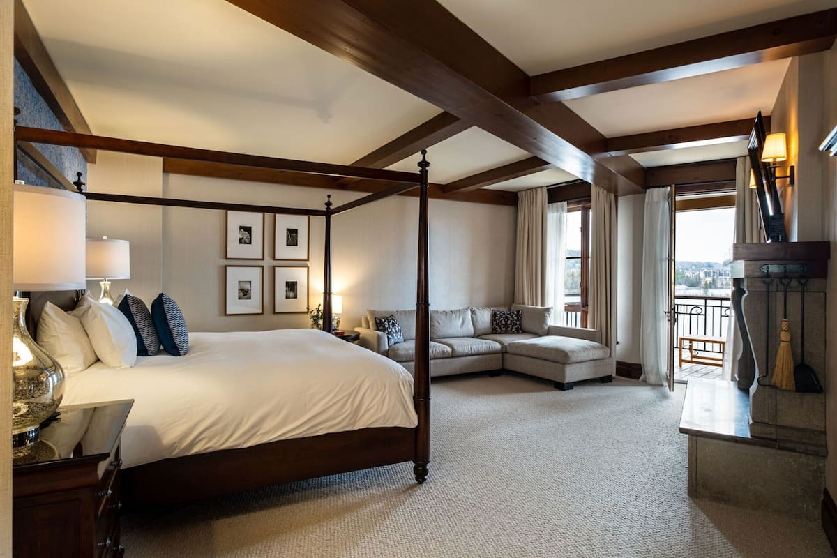 Een slaapkamer met een hemelbed, een bank, uitzicht op de stad en een balkon met een bezem.