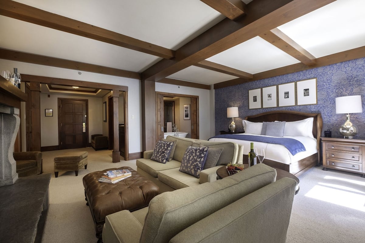 Een hotelkamer met een groot bed, een bank, een bijzettafeltje en een houten plafond.
