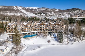 Een groot resort met meerdere gebouwen, een zwembad en een besneeuwde berg op de achtergrond.