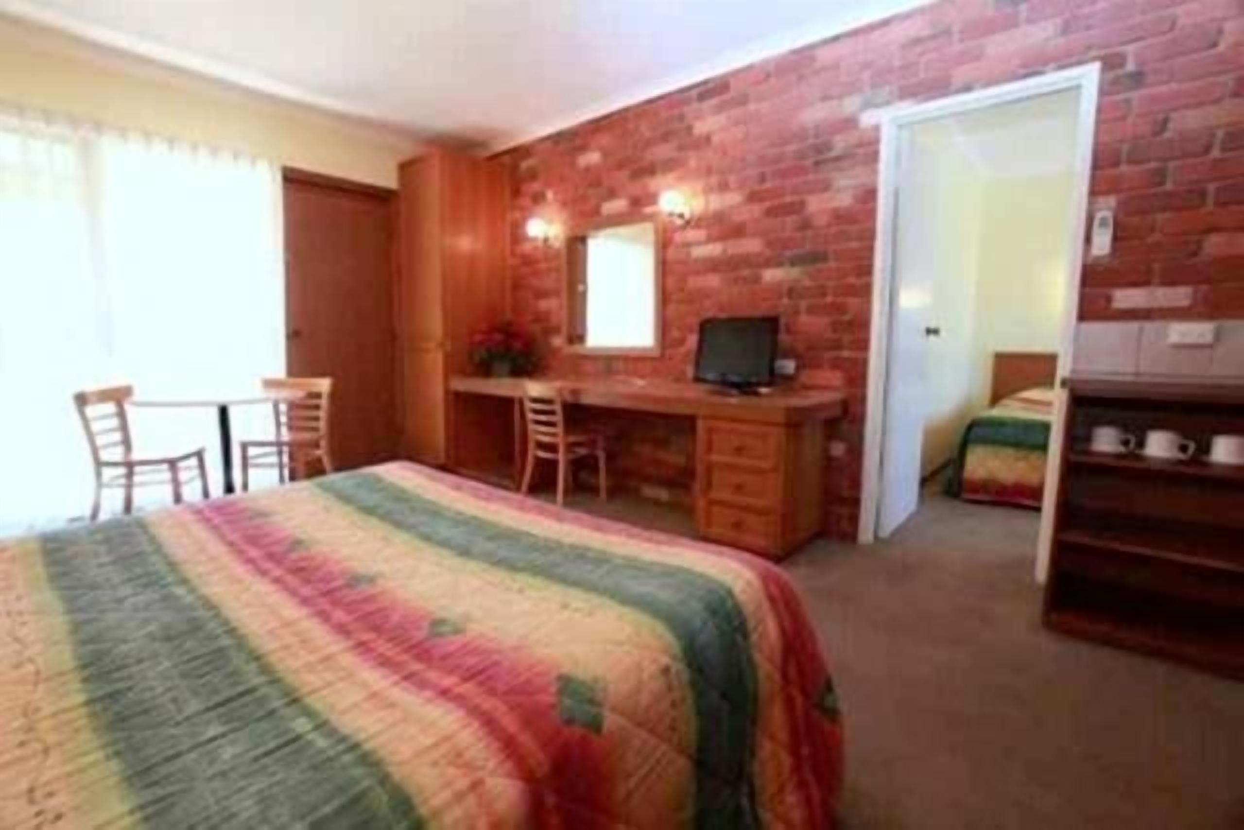 Un dormitorio con una cama, un escritorio y una silla.