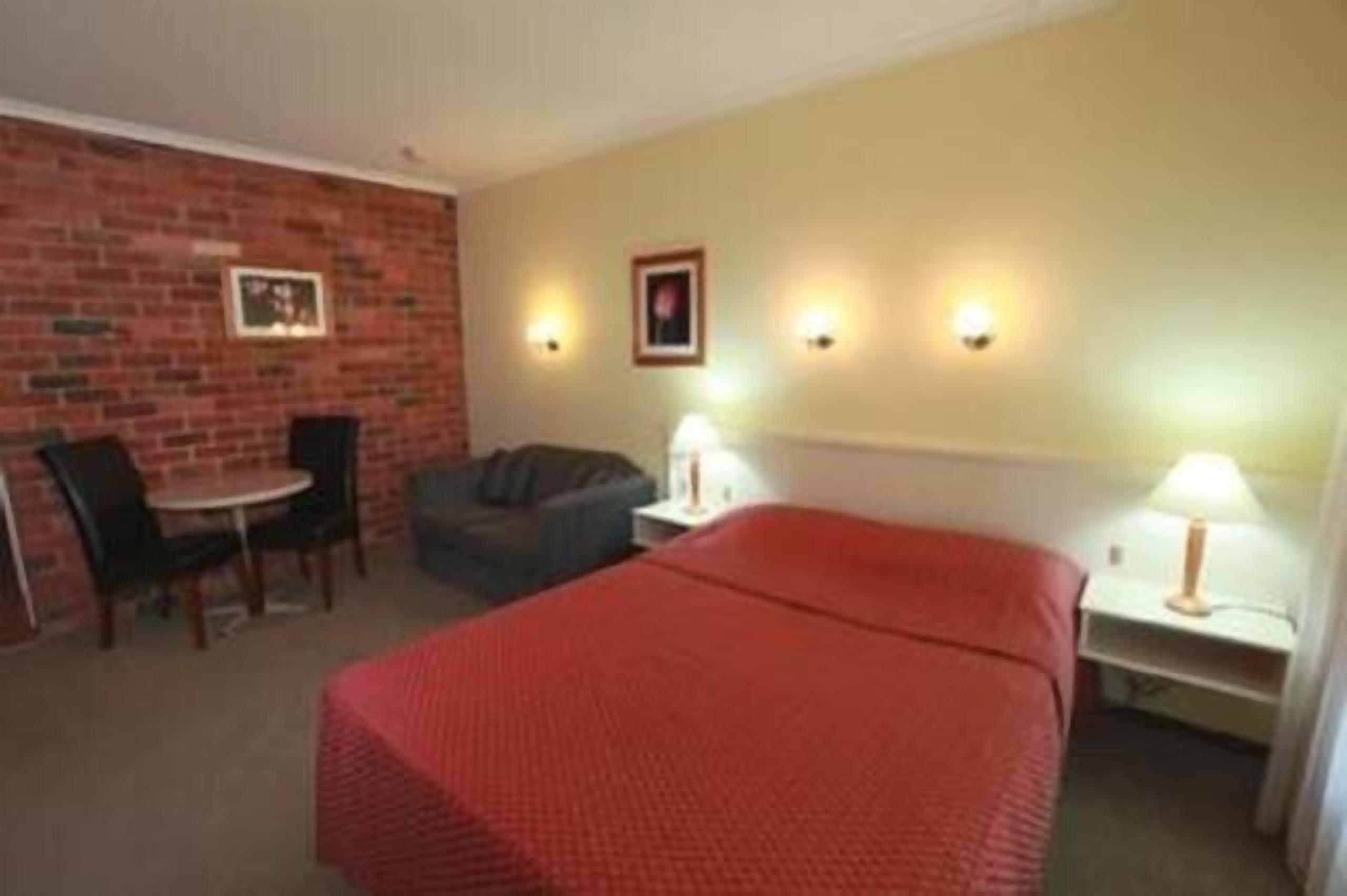 Una habitación de hotel con cama, escritorio, silla y sofá.