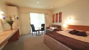 Habitación de hotel con cama, escritorio, silla y una mesita.