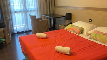 Une chambre d’hôtel avec un grand lit, un bureau, une chaise et une fenêtre avec des rideaux.