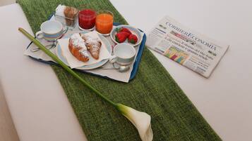 A breakfast tray with croissants, strawberries, juice, and a newspaper on a green mat.