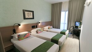 Quarto de hotel com duas camas, uma escrivaninha, uma cadeira, uma televisão e um quadro na parede.