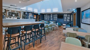 A modern restaurant with a bar area, wooden flooring, and a variety of seating options including bar stools and tables. - Travelodge London Central Southwark (London)