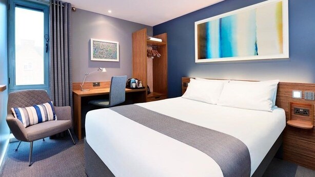A hotel room with a large bed, a desk, a chair, and a wardrobe. - Travelodge London Central Southwark (London)