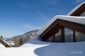 A snow-covered mountain landscape with a building featuring large windows and a sloped roof. - Neve Sole Folgarida Resort Aparthotel (Dimaro Folgarida)