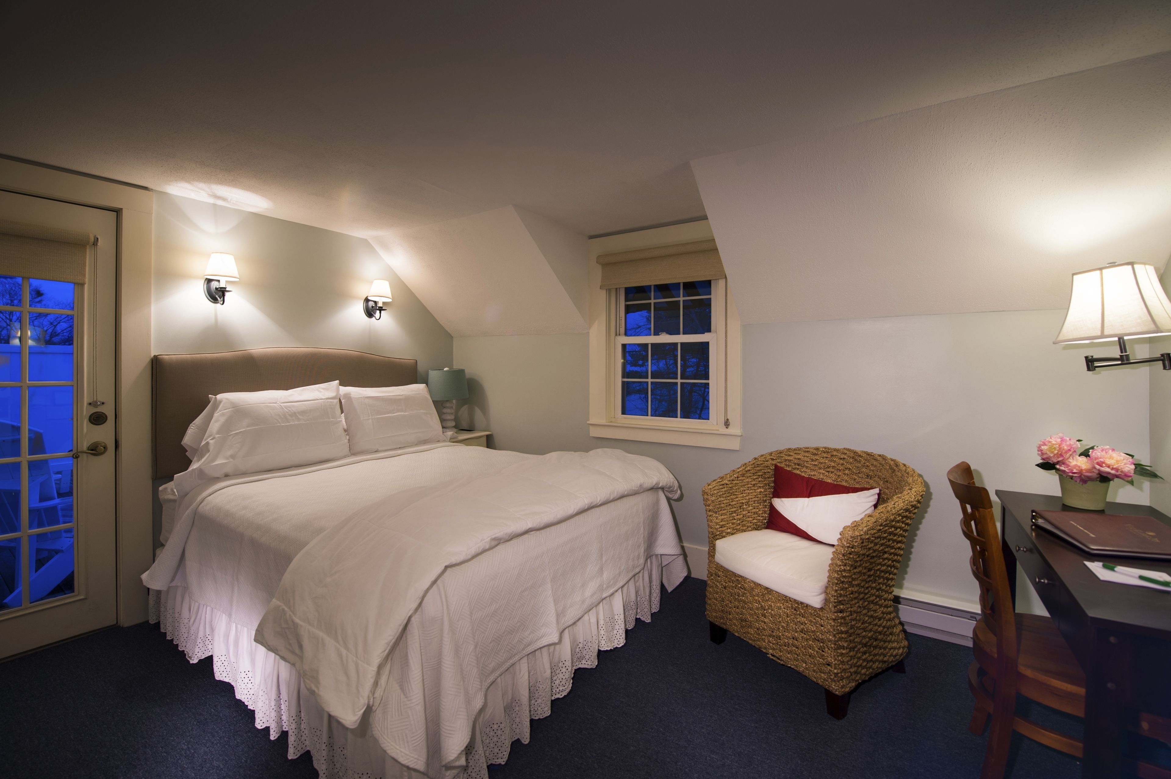 A bedroom with a bed, a chair, a desk, and a window.