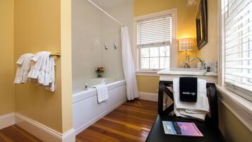 A bathroom with a bathtub, a sink, and a vanity table.