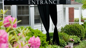 A house with a black and white striped awning labeled "ENTRANCE" and a garden with pink flowers. - York Harbor Inn (York Harbor)