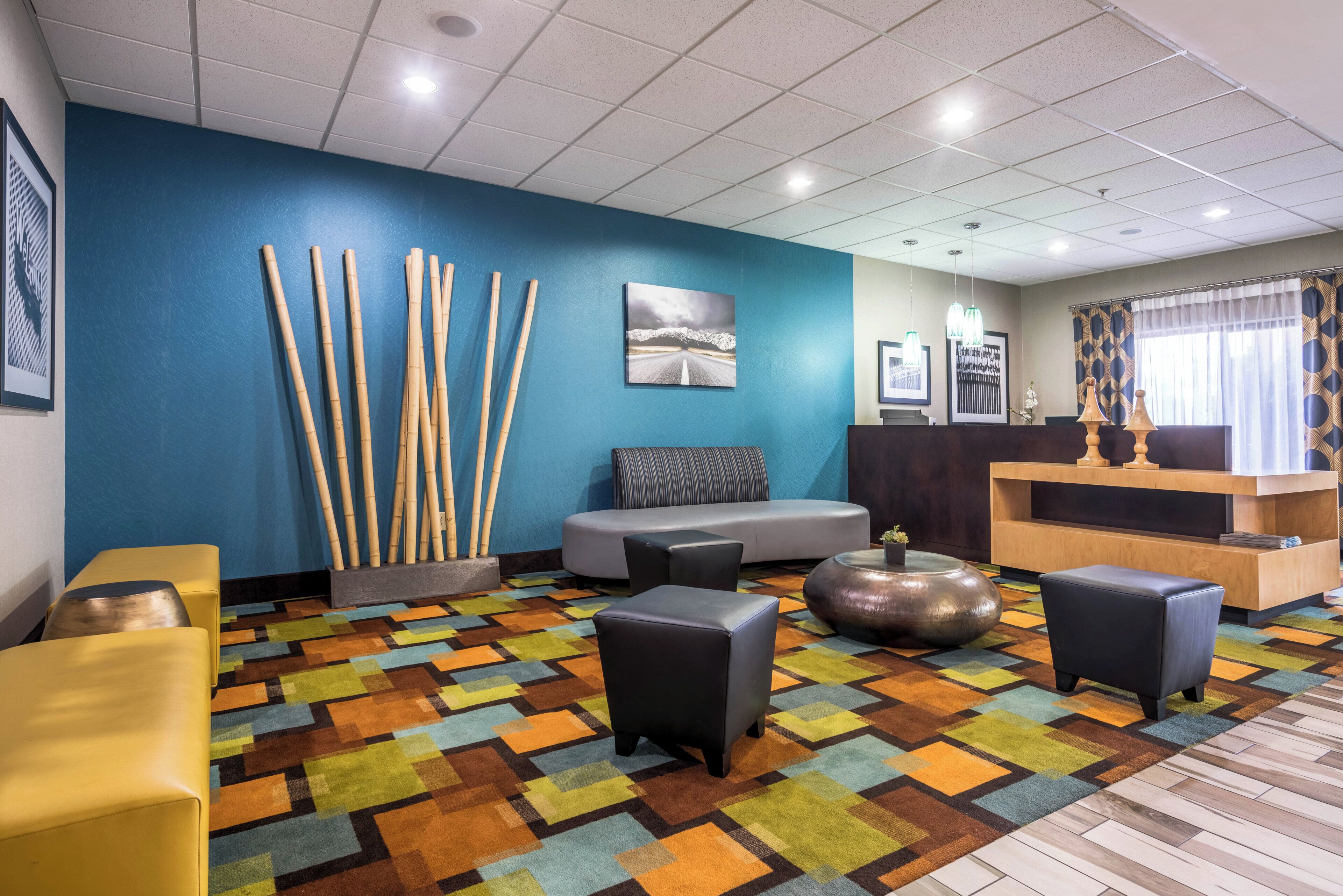 A reception area with a blue wall, a reception desk, a seating area with a sofa and chairs, and a patterned carpet.