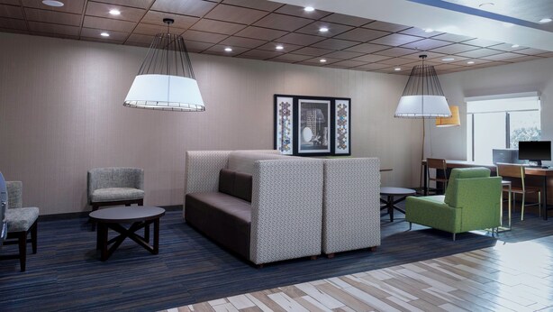 A hotel lobby with a seating area, a reception desk, and a television. - Holiday Inn Express & Suites Roanoke Rapids SE by IHG (Roanoke Rapids)