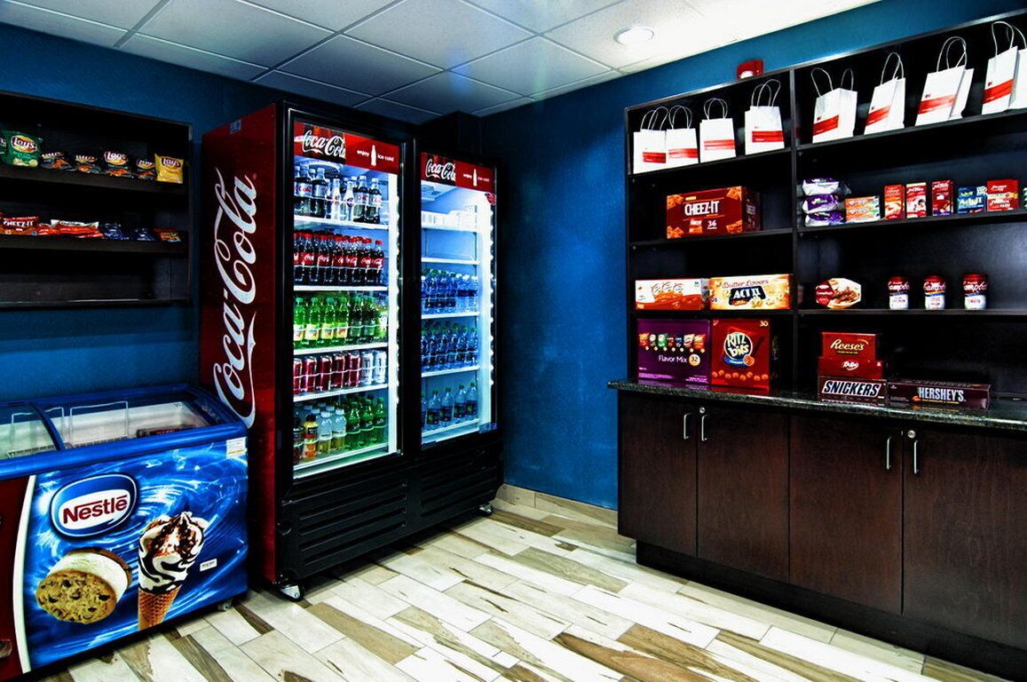 A vending area with Coca-Cola and Nestle machines, and shelves stocked with snacks like Reese's, Snickers, and Hershey's.