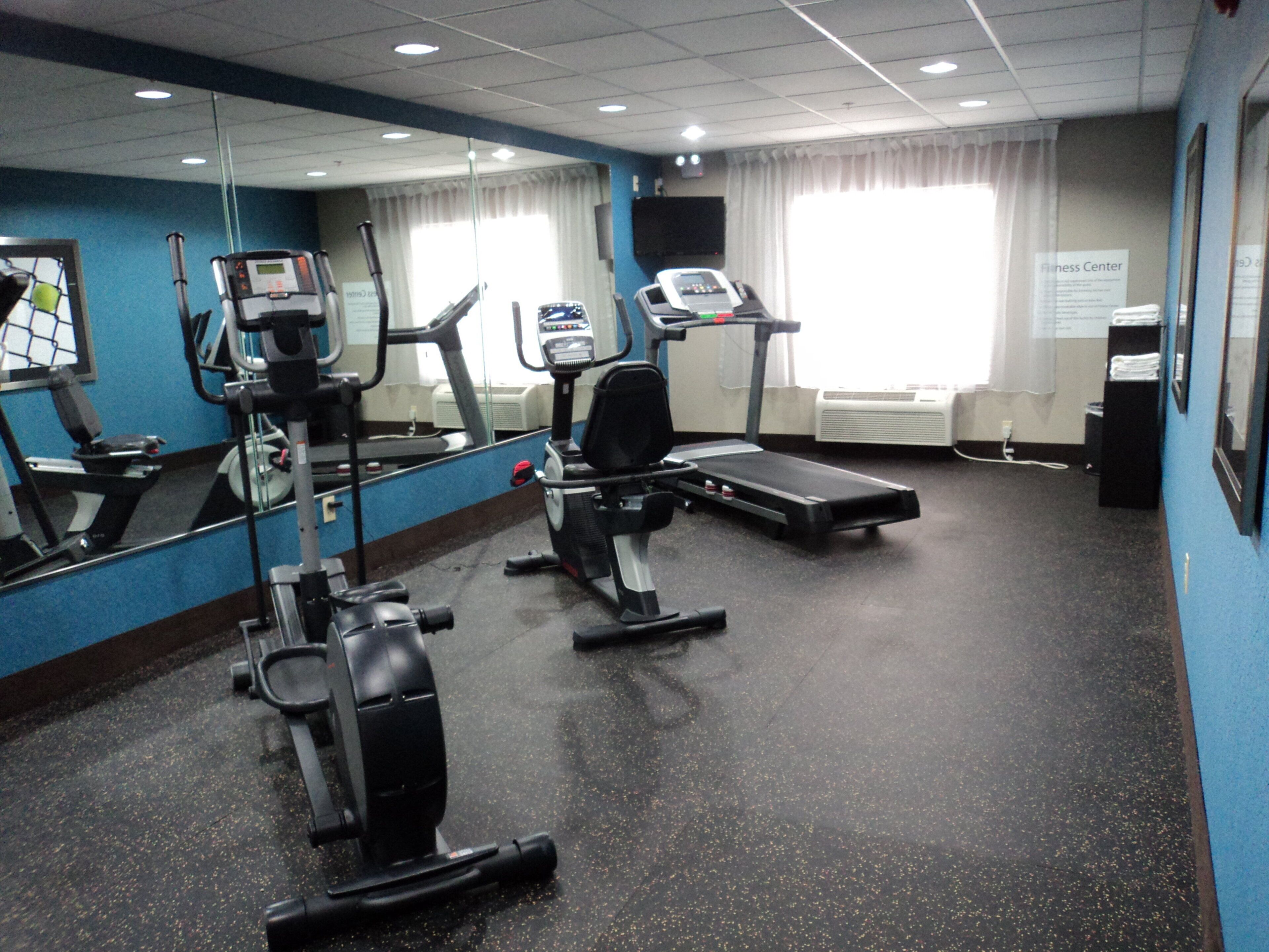 Un gimnasio con equipo de ejercicio, un espejo grande y un cartel con la ubicación.
