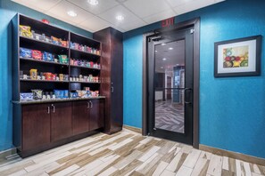 A hallway with a snack shelf stocked with various chips and a door marked 'EXIT'. - Holiday Inn Express & Suites Roanoke Rapids SE by IHG (Roanoke Rapids)