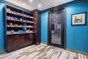 A hallway with a snack shelf stocked with various chips and a door marked 'EXIT'.