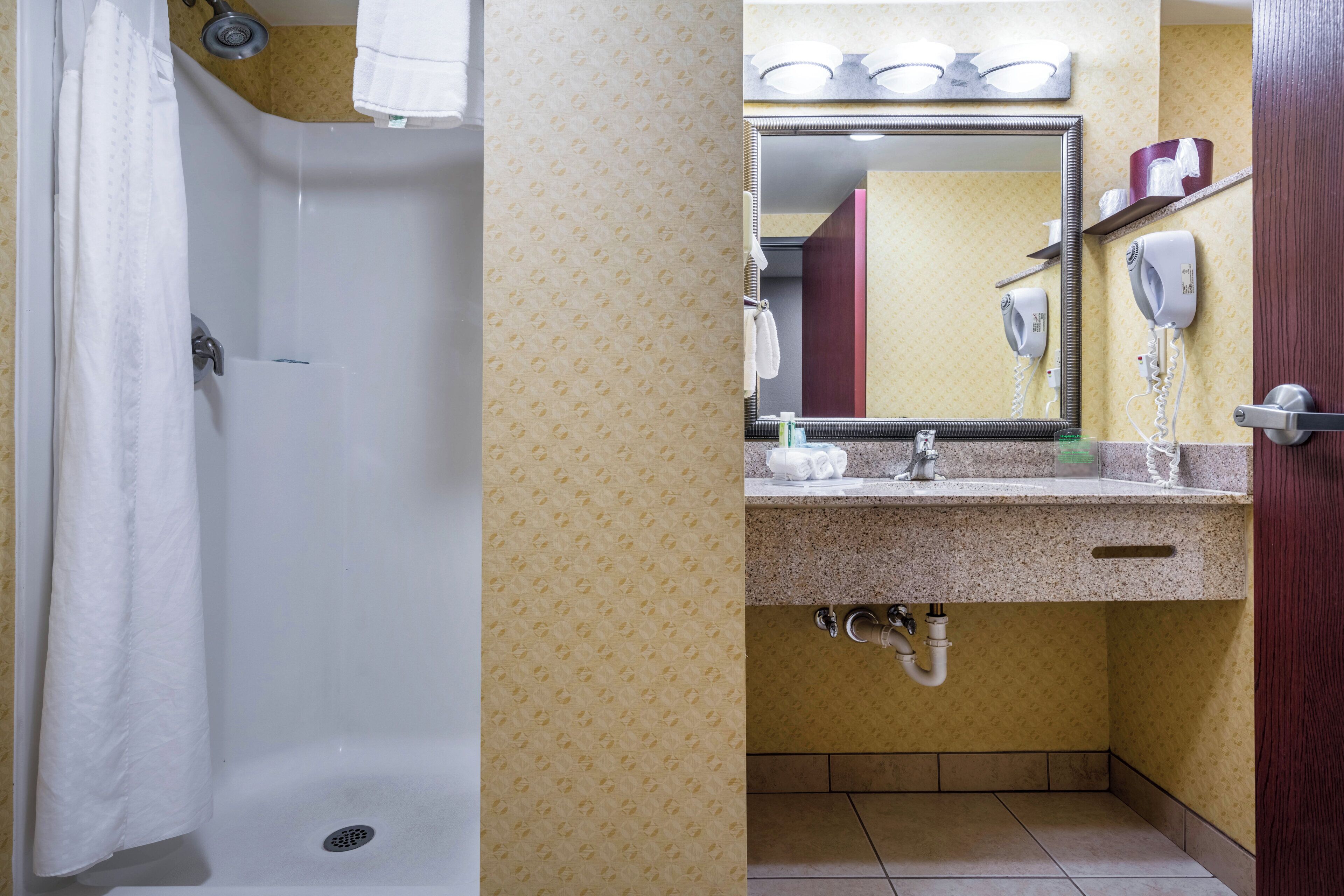 A bathroom with a bathtub, a sink with a mirror, and a hairdryer.