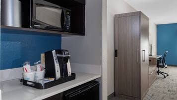 Una kitchenette equipada con microondas, cafetera y tazas de café.