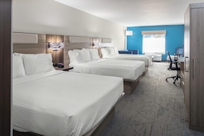 Habitación de hotel con dos camas, un escritorio, una silla y un televisor.