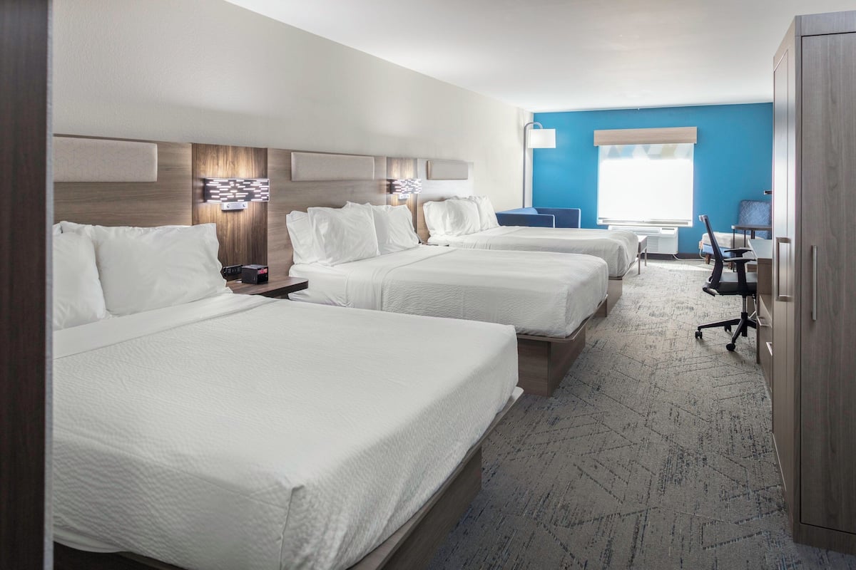 A hotel room with two beds, a desk, and a chair.