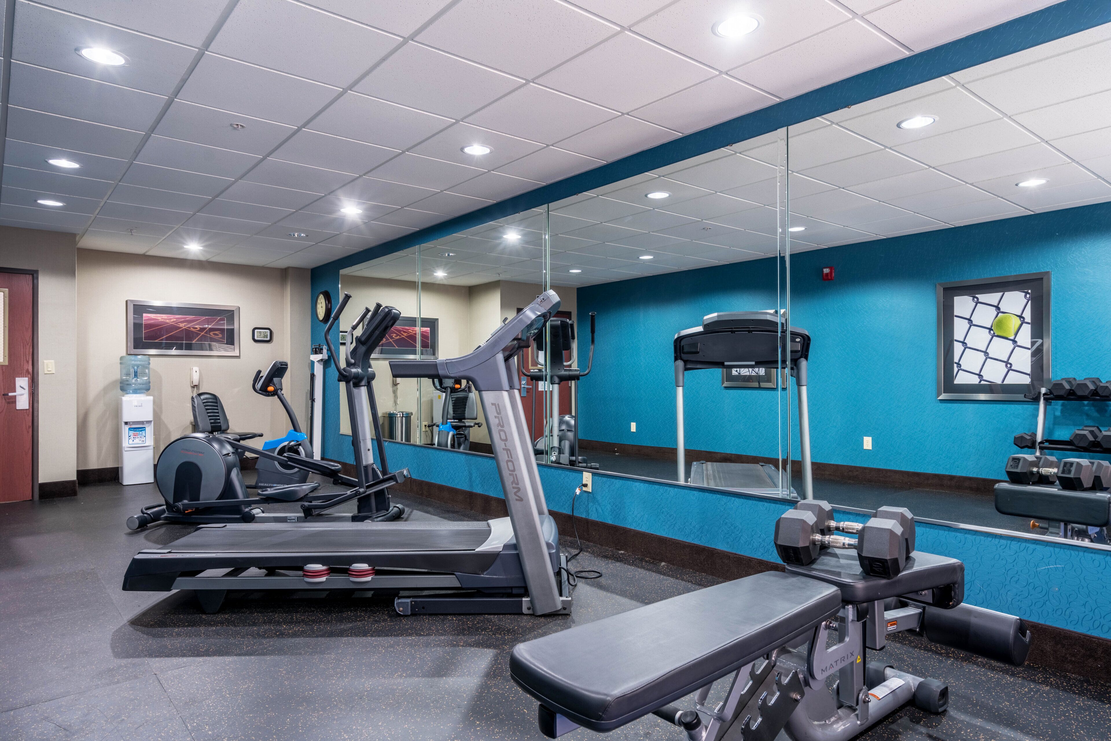 A gym with exercise equipment, a water dispenser, and a mirror.