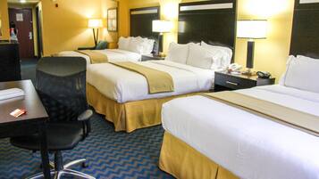A hotel room with two beds, a desk, a chair, and a telephone.